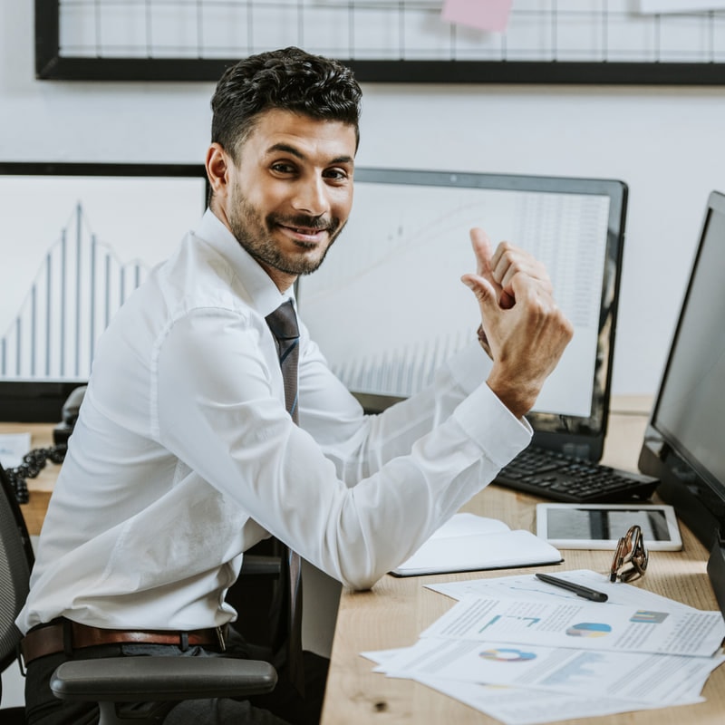 Procurement specialist at his desk pointing at a chart on screen